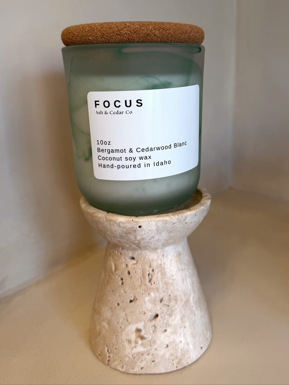 Frosted sage green Focus candle with cork lid, Bergamot &  Cedarwood Blanc scent, on travertine stand
