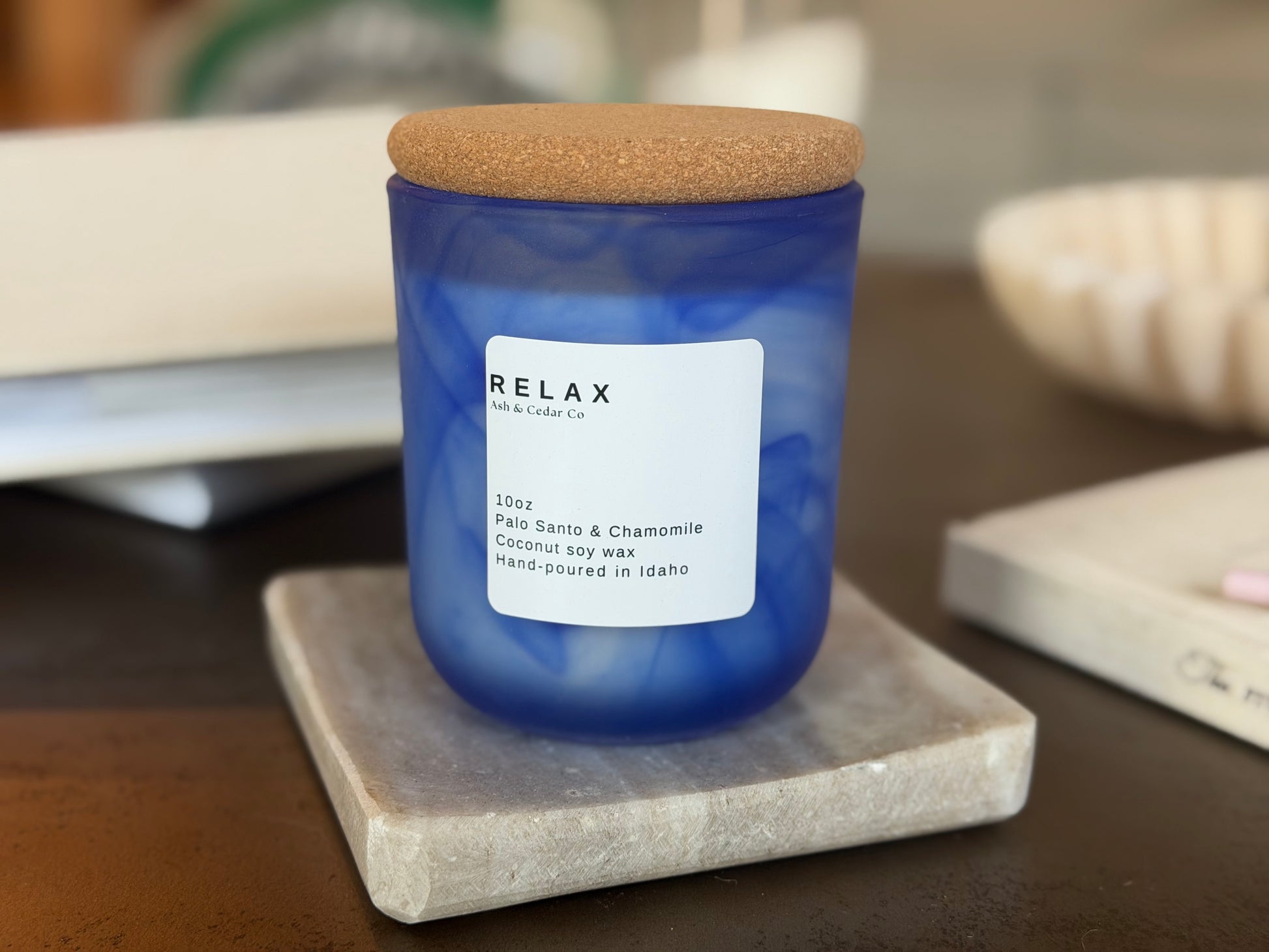 White jar Relax candle with cork lid, Palo Santo & Chamomile scent, on travertine stand